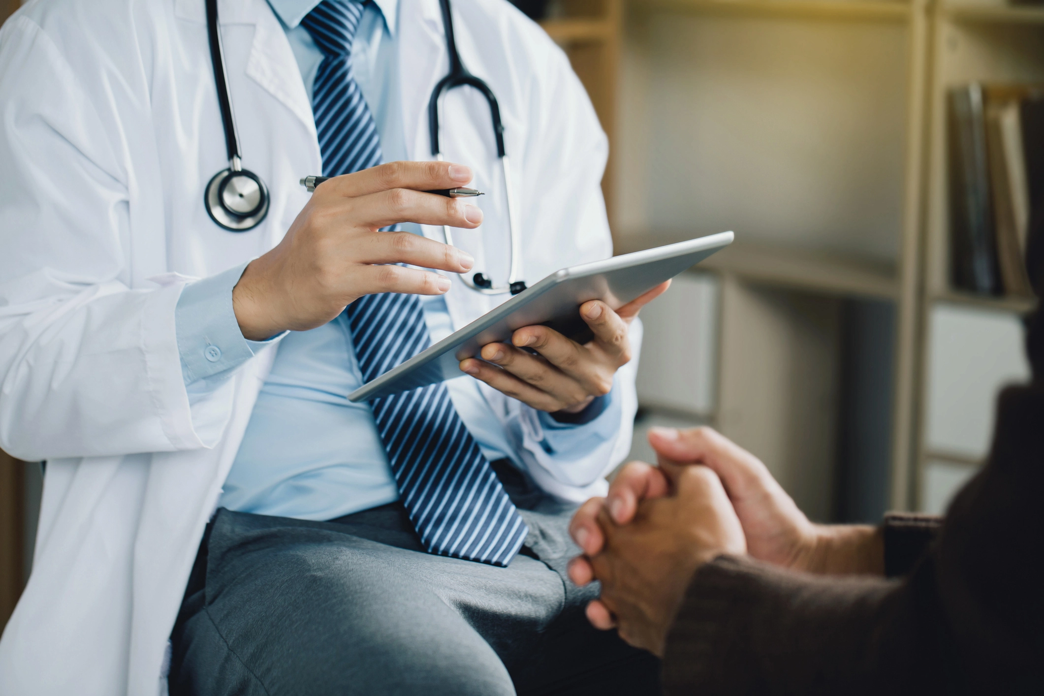 Doctor wearing a coat and a stethoscope, holding a pen and a tablet computer